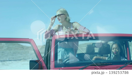 Adjusting sunglasses one friend while other drives red jeep on salt flat, with wristwatch, cardigan Adjusting sunglasses one friend while other drives red jeep on salt flat, with wristwatch, cardigan 139253786