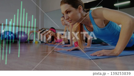 Instructor in tank top leading group doing push-ups on mats in fitness studio with Swiss balls Instructor in tank top leading group doing push-ups on mats in fitness studio with Swiss balls 139253839