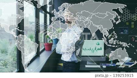 Gazing man wearing light blue shirt by window in office, with computer monitor and potted plants Gazing man wearing light blue shirt by window in office, with computer monitor and potted plants 139253915