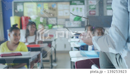 Teacher holding eyeglasses and speaking to students in classroom, with desks, posters, copy space Teacher holding eyeglasses and speaking to students in classroom, with desks, posters, copy space 139253923