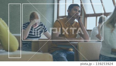 Resting chin, male student in ochre polo shirt gazing right in high school classroom, with desks 139253924