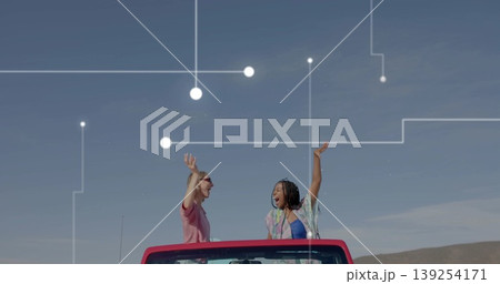 Driving red convertible, two women raising arms on rural road under blue sky, network overlay Driving red convertible, two women raising arms on rural road under blue sky, network overlay 139254171