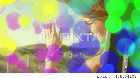 Gazing woman raising left hand on balcony, with rings, metal railing, bokeh overlays, copy space 139254183