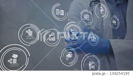 Standing doctor wearing white coat, gloves and stethoscope at clinic, with data icons, copy space 139254195