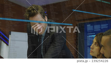 Leaning mid adult man reviewing printed documents in conference room, with laptop and data displays 139254226