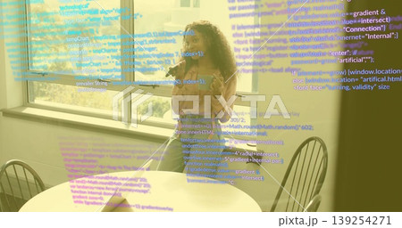 Talking developer woman holding smartphone, gesturing at wooden table by window, with floating code Talking developer woman holding smartphone, gesturing at wooden table by window, with floating code 139254271
