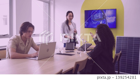 Collaborating business team designing power in boardroom, with solar panels and wind turbine models 139254281