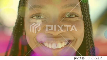 Smiling woman with braided hair showing teeth in sunny portrait, with colorful lens flare overlays Smiling woman with braided hair showing teeth in sunny portrait, with colorful lens flare overlays 139254345