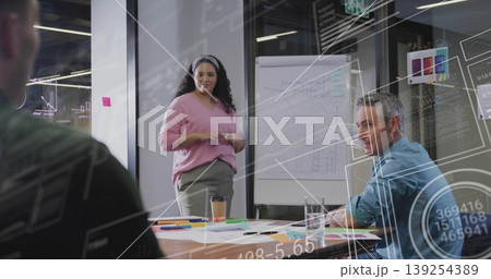 Presenting mid adult female presenter highlighting data overlays in meeting room, with flip chart Presenting mid adult female presenter highlighting data overlays in meeting room, with flip chart 139254389