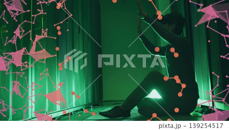 Kneeling technician in dark outfit touching server rack in datacenter green lighting, pink overlay Kneeling technician in dark outfit touching server rack in datacenter green lighting, pink overlay 139254517