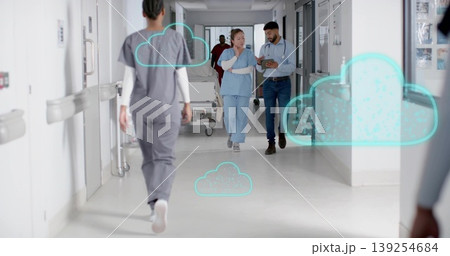 Walking co-workers in scrubs and business shirts using tablet in hospital hallway, with cloud icons 139254684
