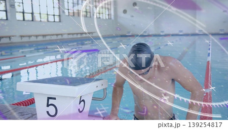 Leaning male swimmer adjusting cap and goggles at poolside, with block 5 and red-blue lane ropes Leaning male swimmer adjusting cap and goggles at poolside, with block 5 and red-blue lane ropes 139254817