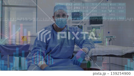Sitting surgeon wearing blue scrubs mask at operating table in OR suite with trolley, data overlays Sitting surgeon wearing blue scrubs mask at operating table in OR suite with trolley, data overlays 139254900