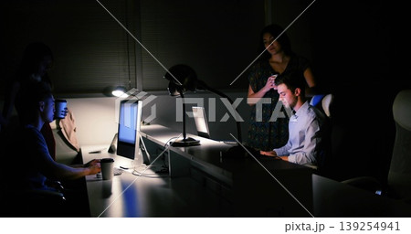 Typing man in button-down shirt at late-night office desk, with laptop, smartphone, mug, copy space Typing man in button-down shirt at late-night office desk, with laptop, smartphone, mug, copy space 139254941