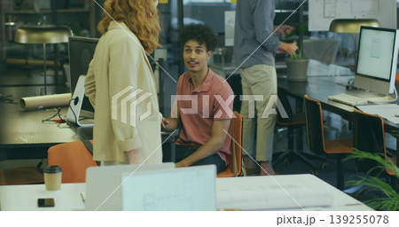 Man in pink polo listening to colleague sharing plan in modern open-plan office, with laptop Man in pink polo listening to colleague sharing plan in modern open-plan office, with laptop 139255078