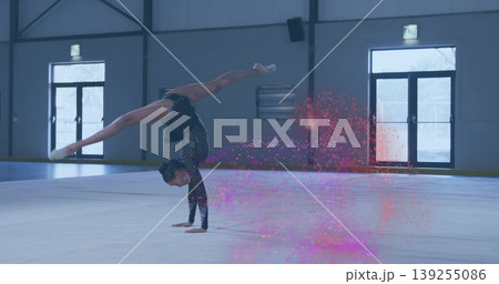 Balancing gymnast executing one-arm handstand split on floor in gym, sparkly leotard, pink powder 139255086