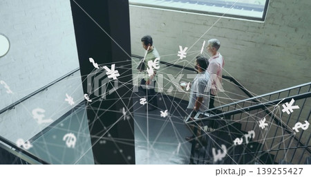 Descending team holding smartphone, tablet, laptop on office railing with floating currency symbols 139255427