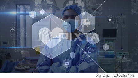 Standing female surgeon wearing blue scrubs in operating room, with tray and floating health icons Standing female surgeon wearing blue scrubs in operating room, with tray and floating health icons 139255475