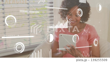 Analyzing woman wearing pink blouse reviewing overlays on tablet on sofa in living room, copy space 139255509