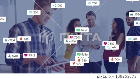 Collaborating professionals discussing social metrics on tablet and laptop in office with icons Collaborating professionals discussing social metrics on tablet and laptop in office with icons 139255575
