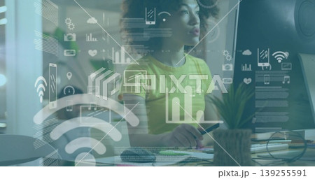 Analyzing woman wearing yellow top monitoring network data at office desk, with overlay graphics Analyzing woman wearing yellow top monitoring network data at office desk, with overlay graphics 139255591
