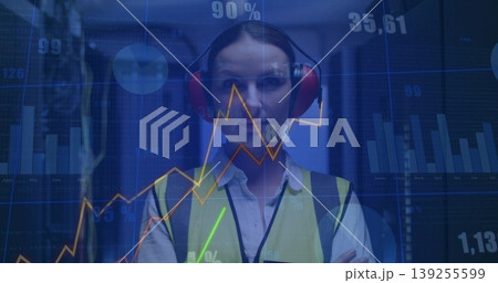 Technician wearing yellow vest red earmuffs inspecting racks in server room, floating data overlays 139255599