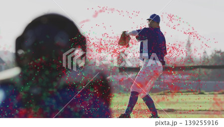 Winding right-handed pitcher releasing baseball on mound at baseball stadium, with catcher's helmet Winding right-handed pitcher releasing baseball on mound at baseball stadium, with catcher's helmet 139255916