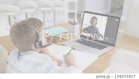 Writing boy in shirt wearing headset sitting at table with laptop, colored pencils, copy space 139255917