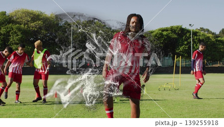 Training male wearing soccer uniform stepping forward on field, with cones and agility hurdles Training male wearing soccer uniform stepping forward on field, with cones and agility hurdles 139255918