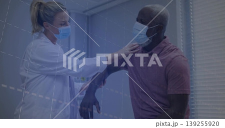 Female doctor assessing male patient shoulder range in exam chair, with lab coat and surgical masks Female doctor assessing male patient shoulder range in exam chair, with lab coat and surgical masks 139255920