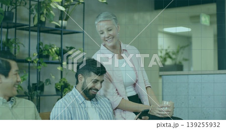 Smiling coworkers leaning around tablet on bench in office lounge, with mug and shelving unit Smiling coworkers leaning around tablet on bench in office lounge, with mug and shelving unit 139255932