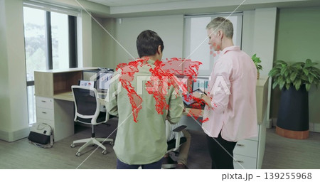 Collaborating colleagues in button-up shirts reviewing tablet in modern office, with dual monitors Collaborating colleagues in button-up shirts reviewing tablet in modern office, with dual monitors 139255968