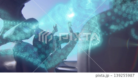 Reaching woman in tshirt and seatbelt touching teal holographic display inside car under sunroof 139255987