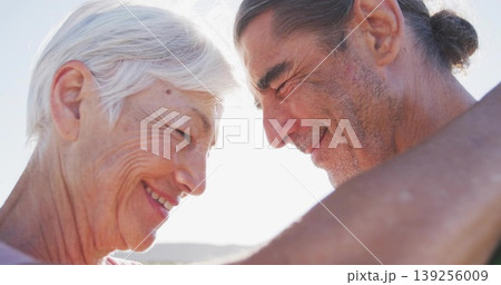 Touching foreheads shirtless man and woman in sleeveless top sharing moment on coast, backlit scene 139256009