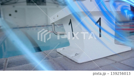 Highlighting white starting block labeled 1 on tiled deck shining under lights, ropes, blue streaks Highlighting white starting block labeled 1 on tiled deck shining under lights, ropes, blue streaks 139256013