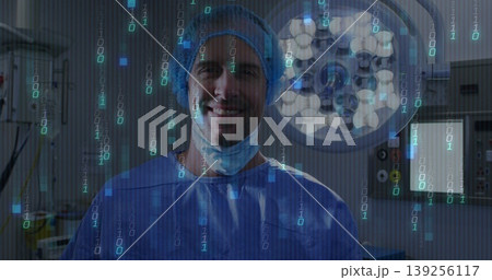 Standing surgeon pulling mask down in blue scrubs under surgical lamp in OR, with binary overlay Standing surgeon pulling mask down in blue scrubs under surgical lamp in OR, with binary overlay 139256117