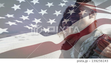 Smiling couple wearing casual attire hugging at sandy beach, with translucent American flag overlay 139256143