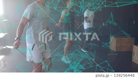 Skipping participant wearing grey t-shirt and shorts inside gym, with skipping ropes, copy space 139256448