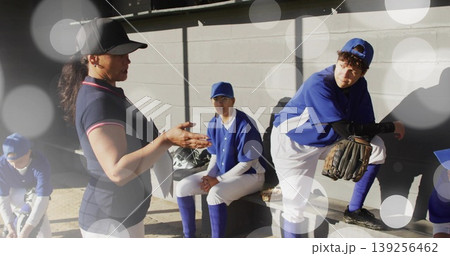 Gesturing coach addressing four players in baseball dugout, with gloves and helmets, copy space 139256462