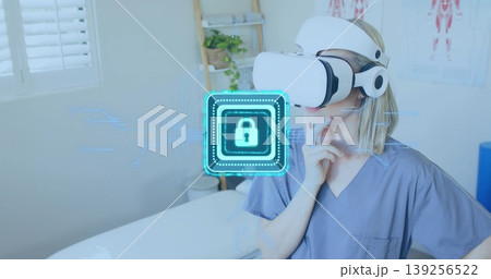 Interacting clinician wearing scrubs, VR headset in exam room, with holographic lock, copy space Interacting clinician wearing scrubs, VR headset in exam room, with holographic lock, copy space 139256522