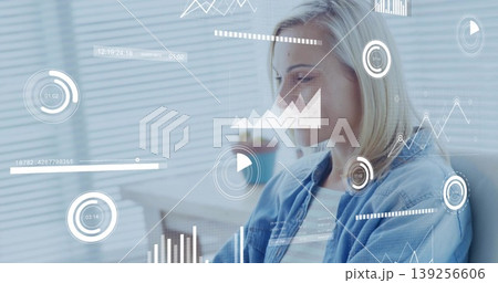 Mid adult woman analyzing floating data charts at office desk, with blinds and plant, copy space 139256606