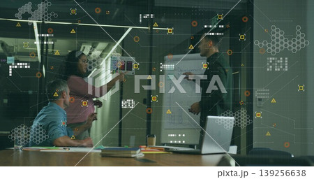 Collaborating business professionals placing sticky notes on glass wall in office, with flipchart Collaborating business professionals placing sticky notes on glass wall in office, with flipchart 139256638