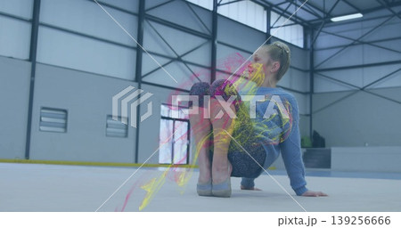 Child gymnast wearing leggings balancing on white mat in gym, with beams, windows and neon trails Child gymnast wearing leggings balancing on white mat in gym, with beams, windows and neon trails 139256666