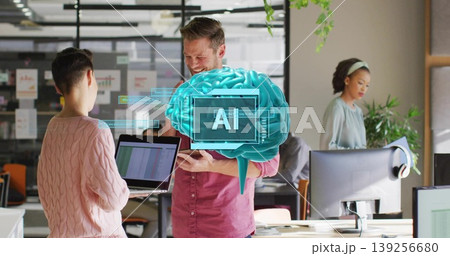 Discussing colleagues wearing business attire sharing laptop in open office, with AI brain graphic 139256680
