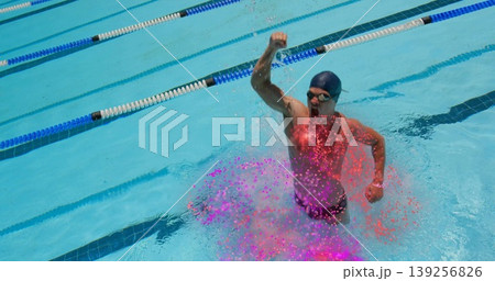 Emerging swimmer thrusting right fist up in outdoor lap pool wearing swim cap, goggles, copy space Emerging swimmer thrusting right fist up in outdoor lap pool wearing swim cap, goggles, copy space 139256826