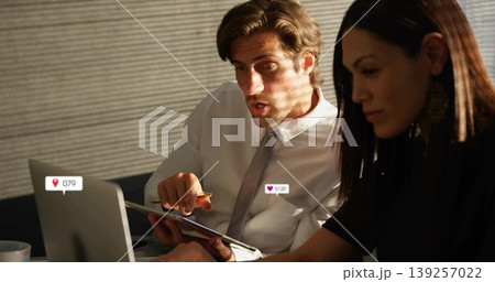 Pointing man and watching colleague discussing report on tablet at office meeting table with laptop 139257022