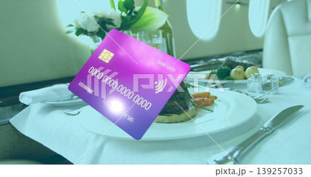 Floating purple-blue bank card displaying EMV chip above jet tray table with steak and vegetables Floating purple-blue bank card displaying EMV chip above jet tray table with steak and vegetables 139257033