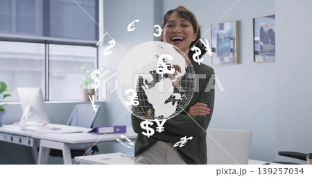 Smiling Asian businesswoman leaning on desk in office, with holographic globe and currency symbols 139257034