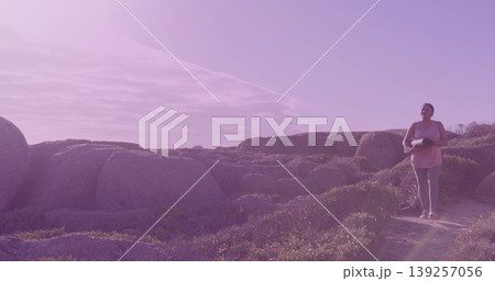 Walking athletic Asian Indian woman carrying yoga mat along coastal trail at sunrise, copy space 139257056