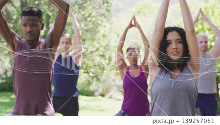 Stretching six yoga practitioners in activewear raising arms overhead on park lawn, with yoga mats 139257081